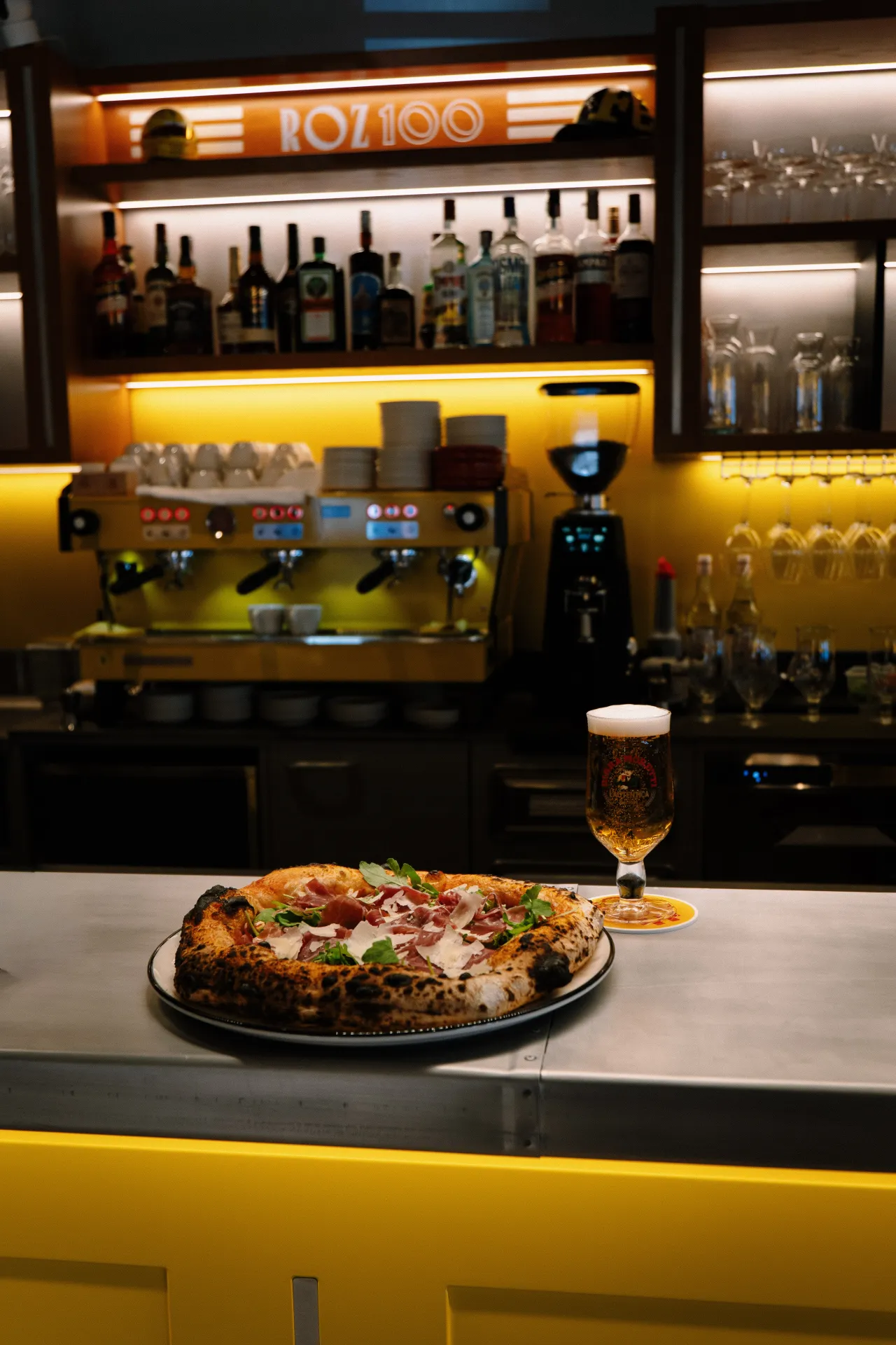 Pizza s pršutom i rikulom na šanku, pivo u čaši